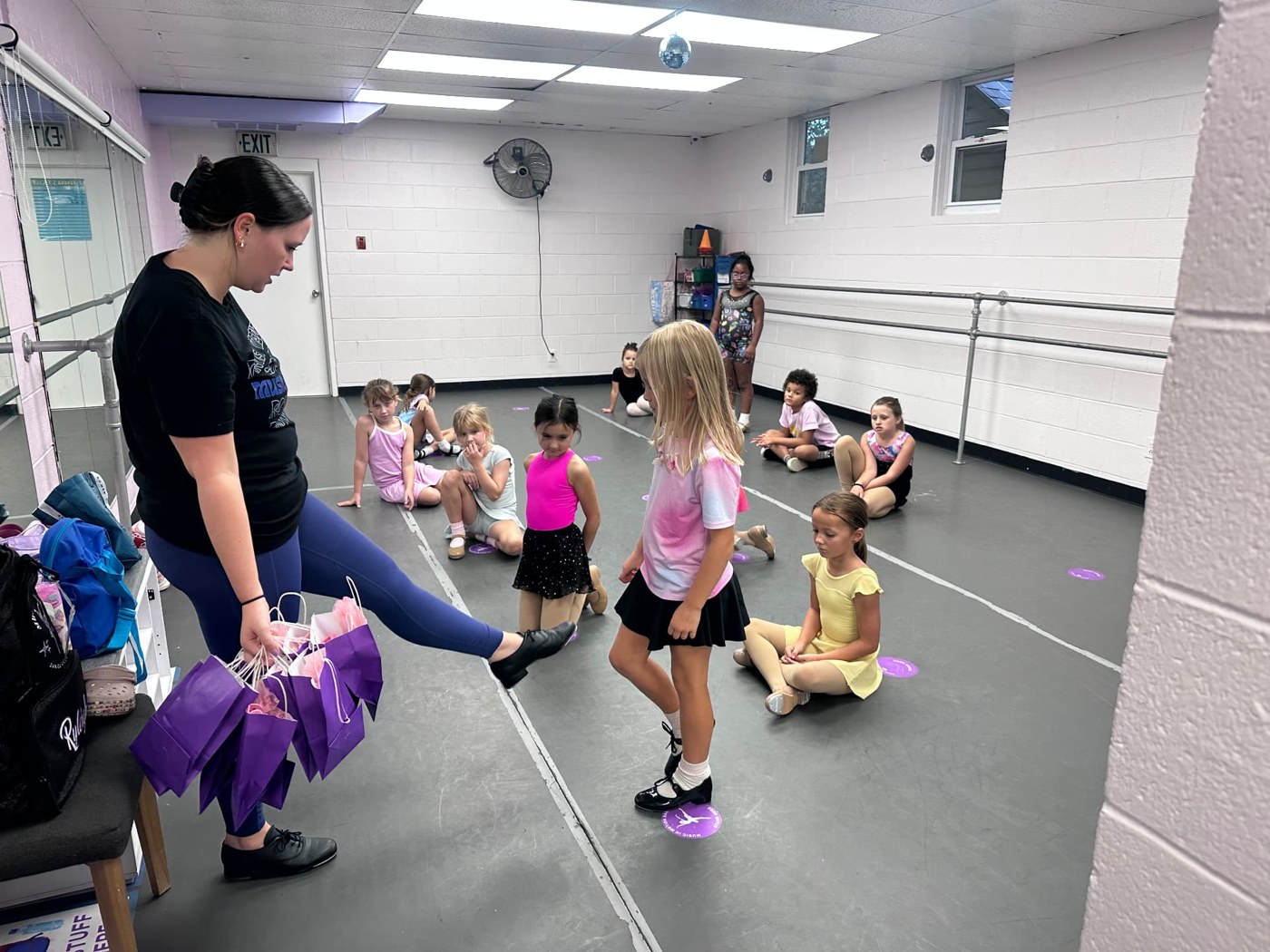 A teacher demonstrating a tap step for a young dancer