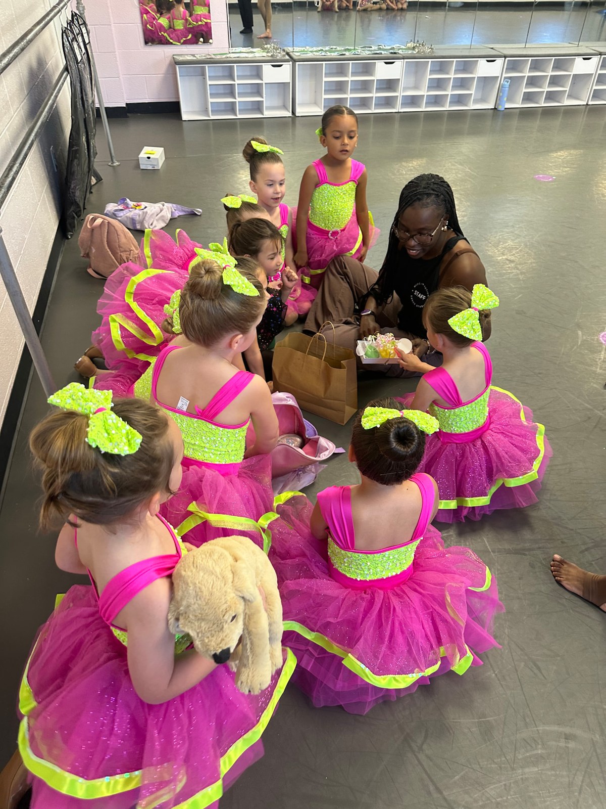 Young dancers gathered around their teacher in the studio