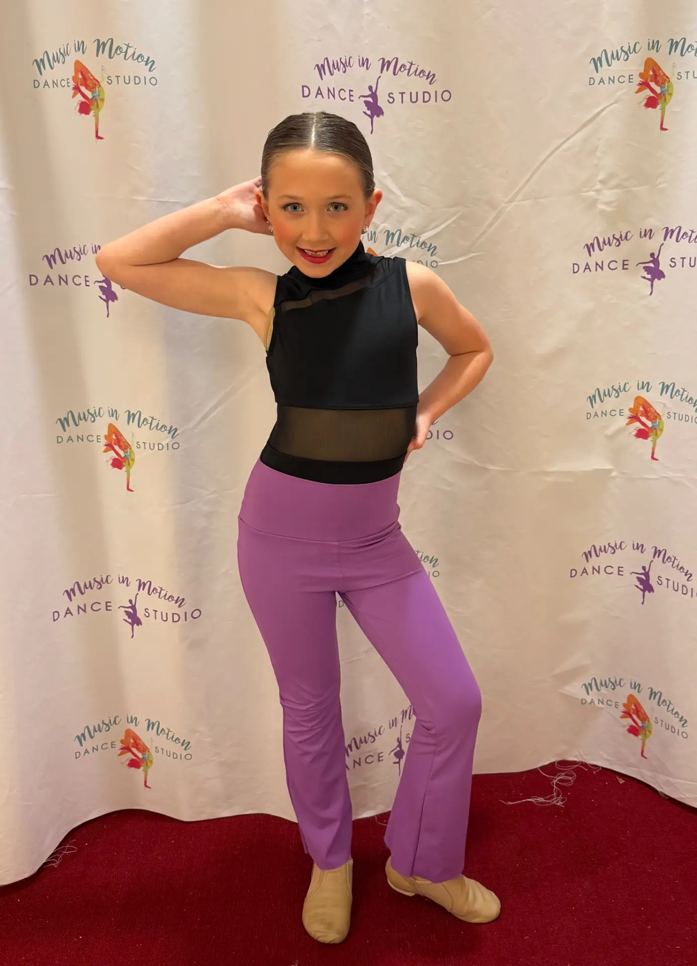 A Music in Motion jazz dancer posing in front of the studio backdrop
