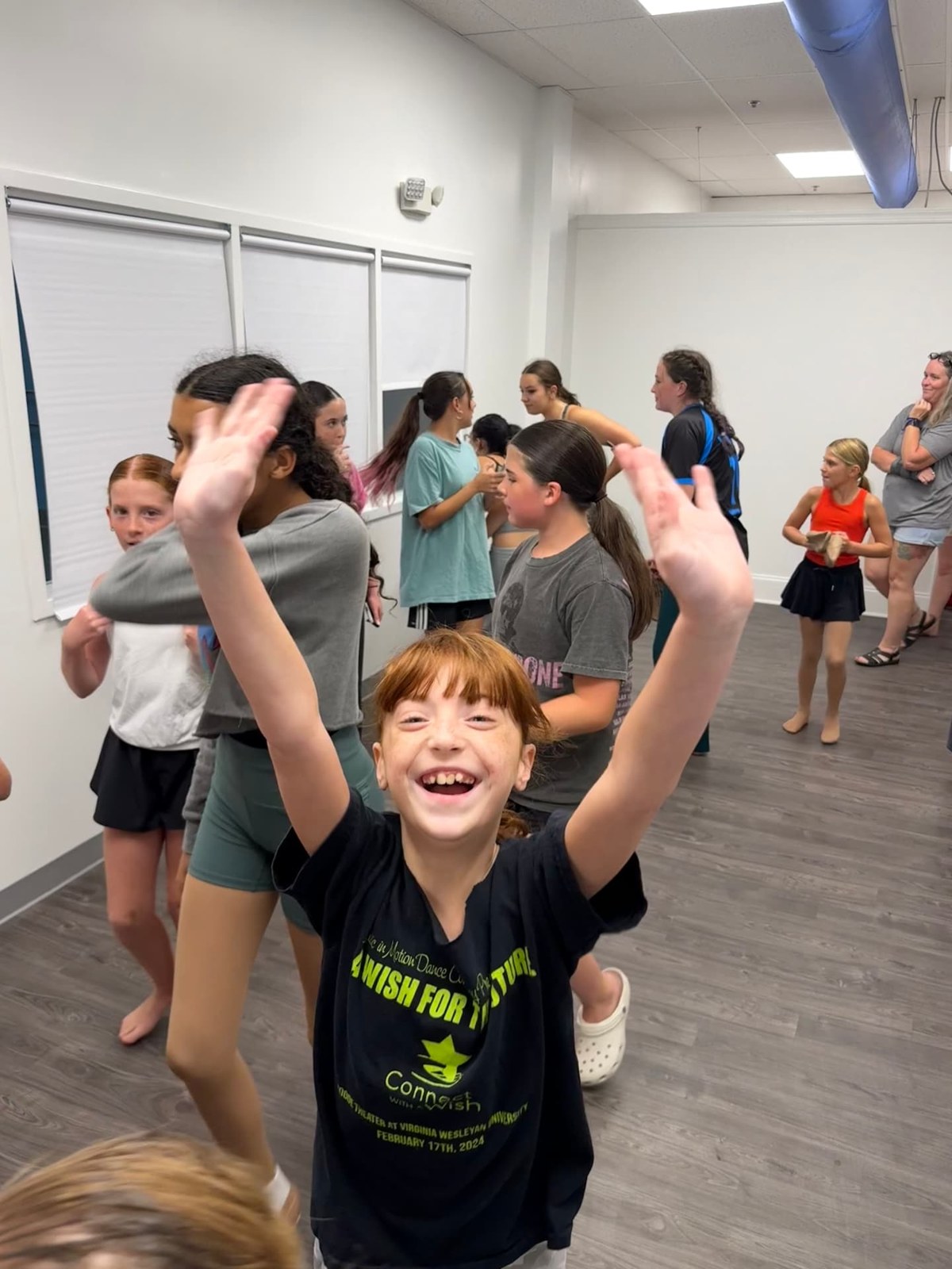 A smiling dancer waving during class