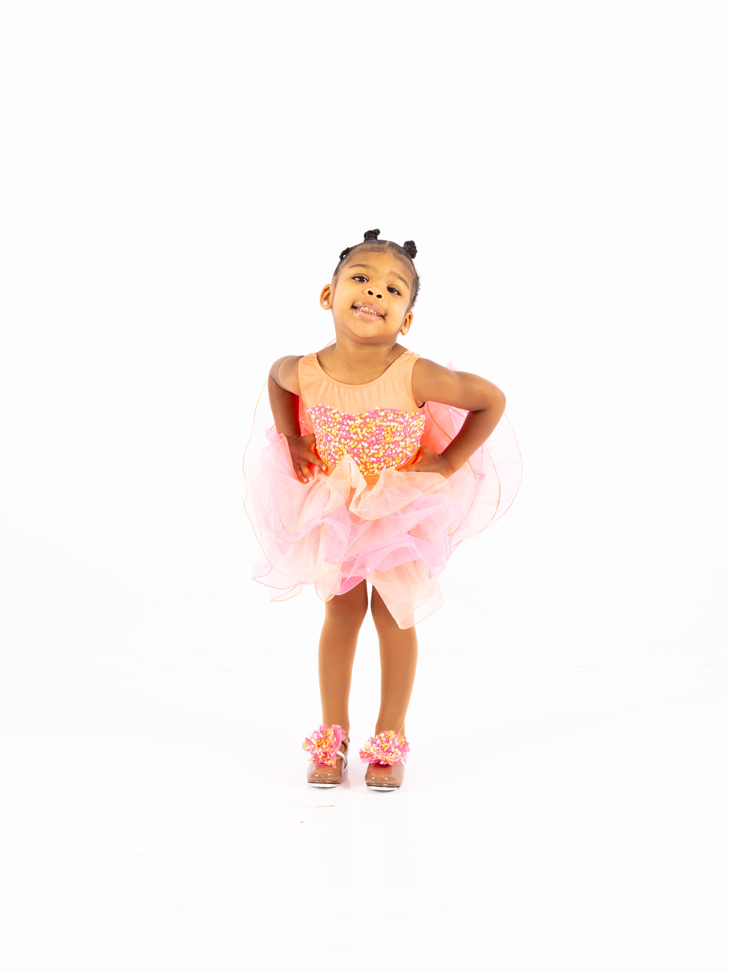 A young tap dancer posing in a peach sequined costume