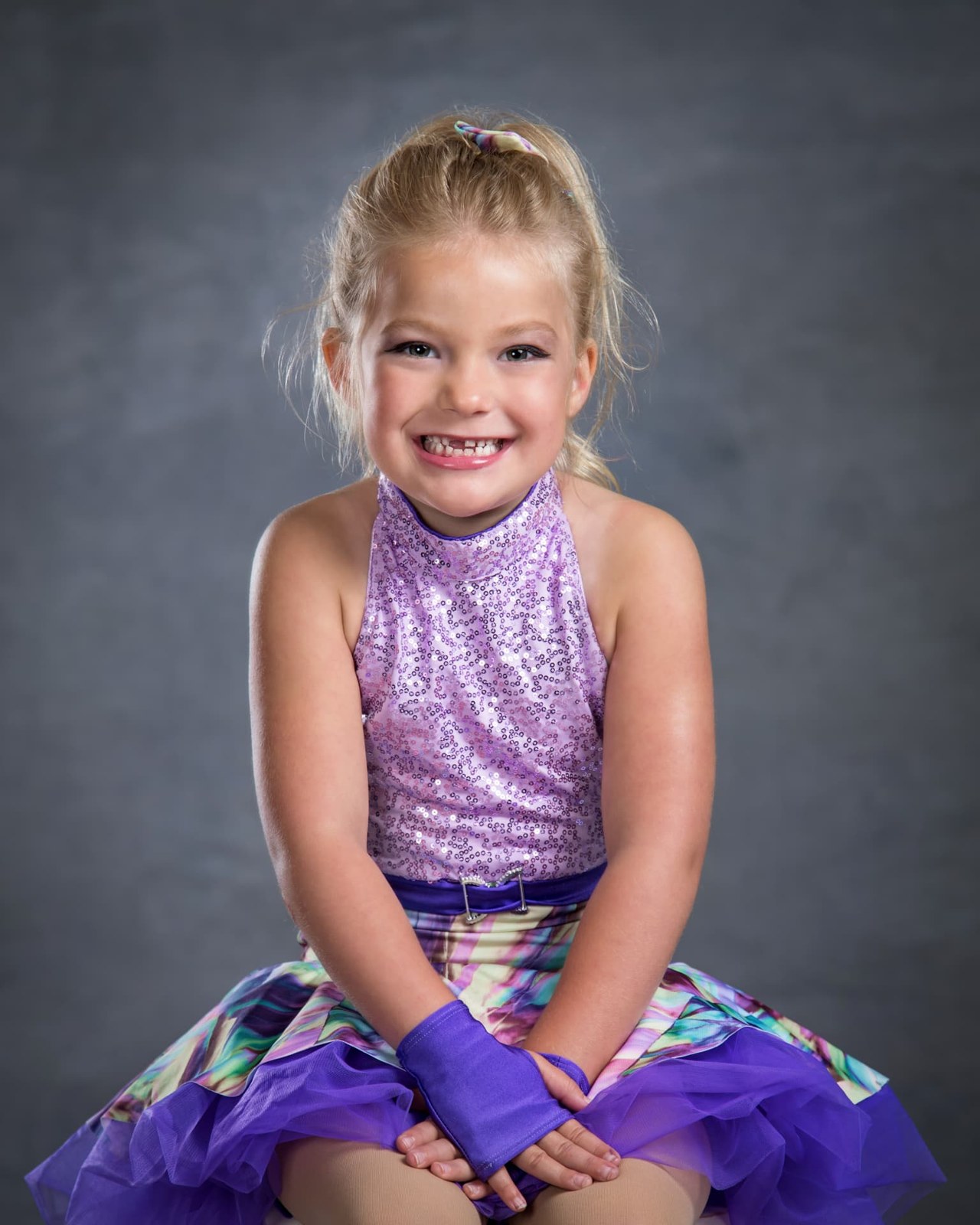 A smiling young dancer in a purple costume
