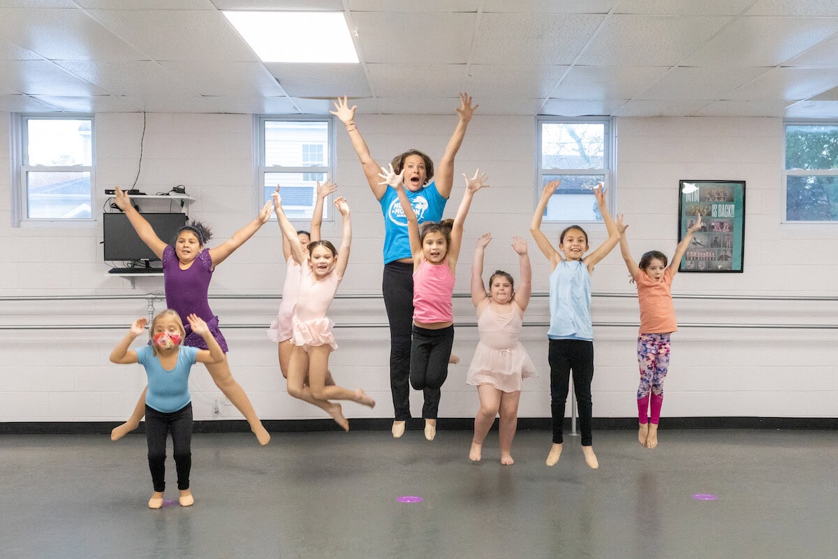 Music in Motion dancers leaping together in a studio class